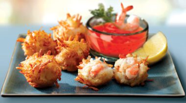 cooked shrimp rolled in potato shreds on blue plate with dipping sauce
