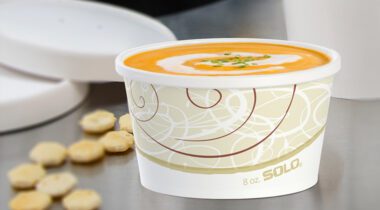 8 oz paper bowl with creamy tomato soup, oyster crackers beside on table